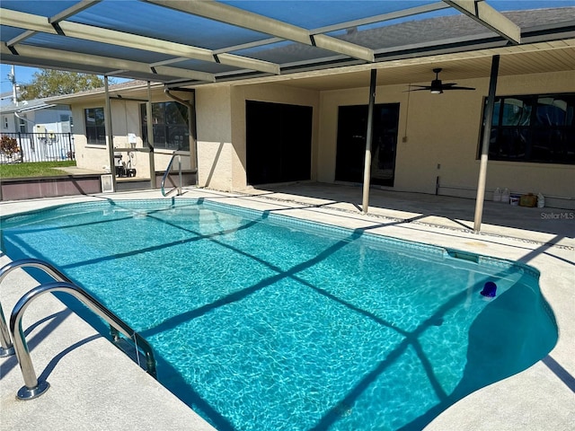 pool with fence, a lanai, a ceiling fan, and a patio area