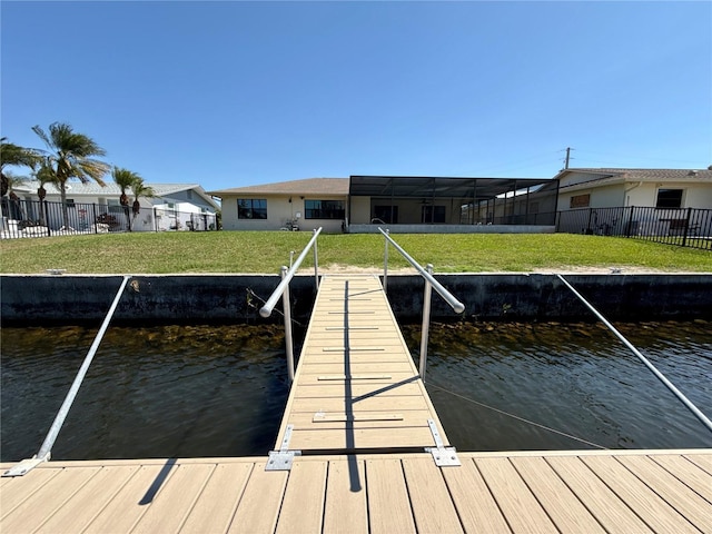 dock area with fence, a water view, and a lawn