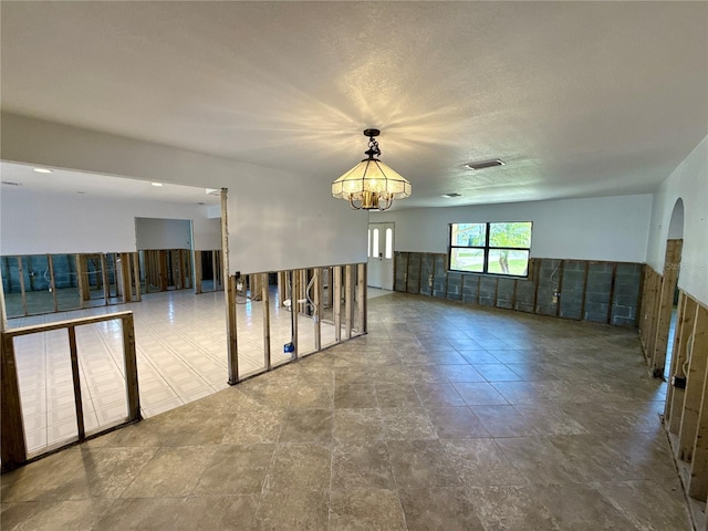 empty room with visible vents, a notable chandelier, and wainscoting