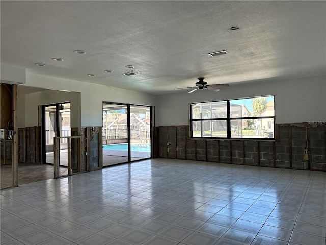 unfurnished room with tile patterned floors, visible vents, wainscoting, and a textured ceiling