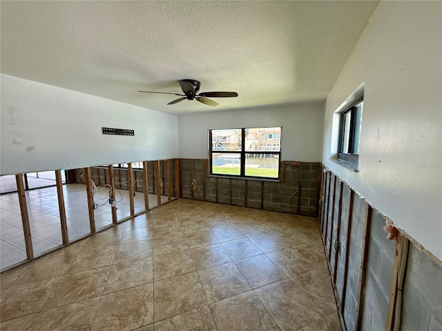 unfurnished room featuring a textured ceiling, wainscoting, and ceiling fan