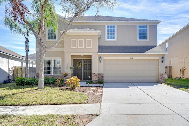 view of front facade featuring an attached garage, fence, stucco siding, stone siding, and driveway