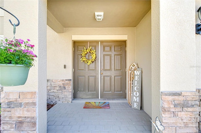 property entrance with stone siding and stucco siding