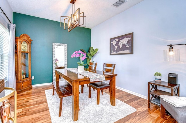 dining space featuring visible vents, baseboards, wood finished floors, and a chandelier