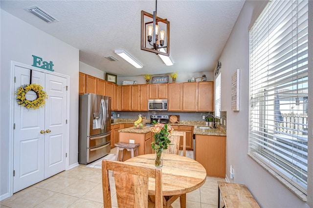 kitchen with a sink, stainless steel appliances, visible vents, and a center island