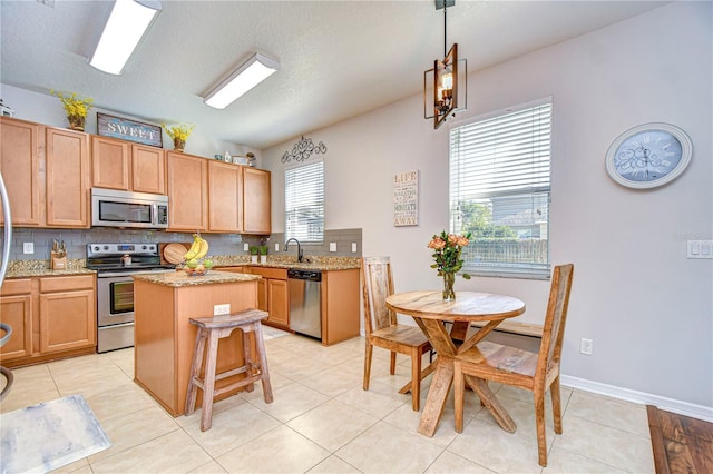 kitchen featuring a sink, decorative backsplash, a kitchen island, and appliances with stainless steel finishes