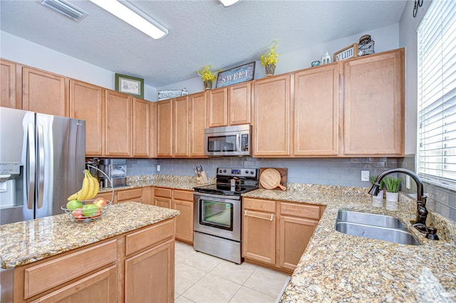 kitchen featuring visible vents, a sink, stainless steel appliances, light tile patterned floors, and decorative backsplash