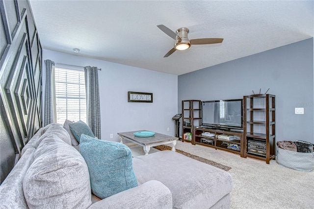 living area with a ceiling fan, carpet floors, and a textured ceiling