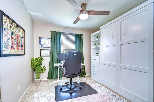 office area featuring light carpet, a ceiling fan, and baseboards