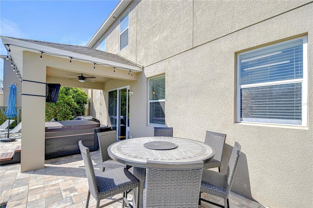 view of patio featuring outdoor dining space, a hot tub, and ceiling fan