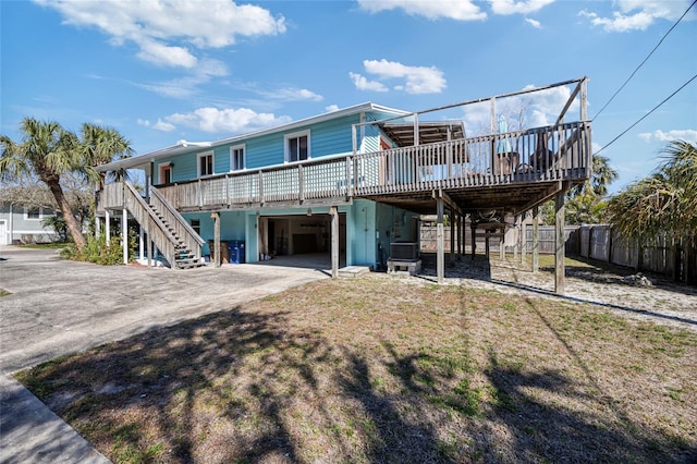 rear view of property with fence, stairway, driveway, a carport, and an attached garage