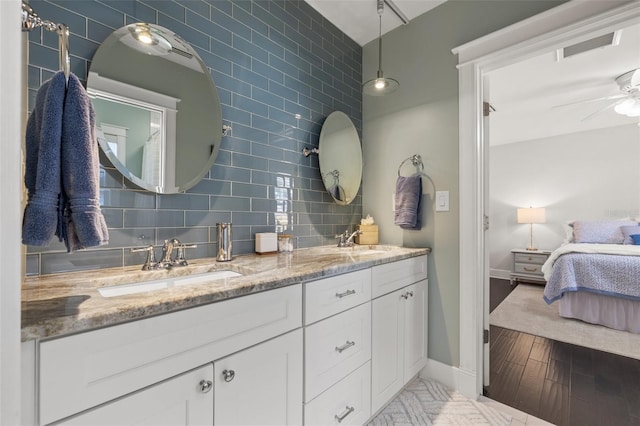 bathroom with double vanity, a ceiling fan, a sink, and ensuite bathroom