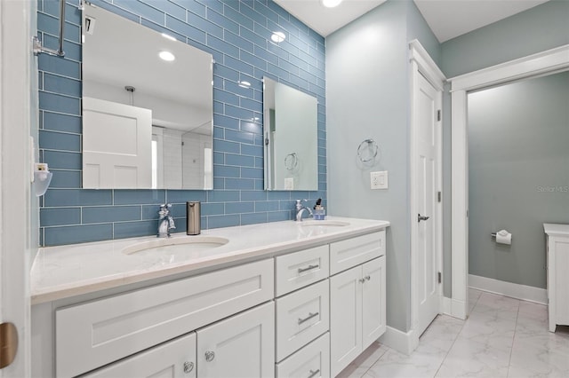full bath with a sink, baseboards, double vanity, and marble finish floor