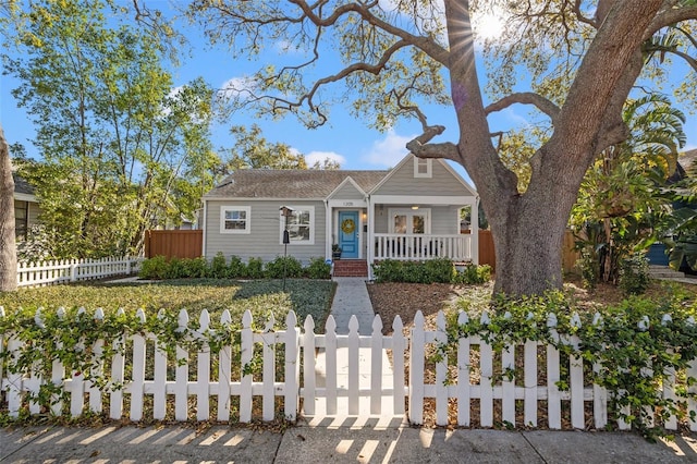 bungalow-style house featuring a fenced front yard and covered porch