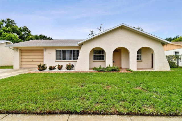 view of front facade with a front yard, an attached garage, driveway, and stucco siding