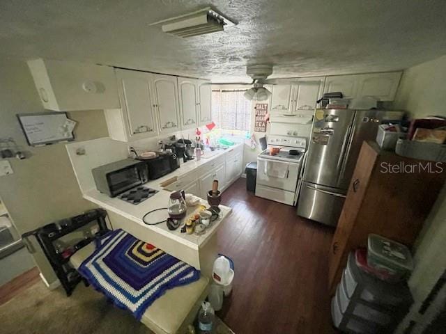 kitchen with white electric range, a textured ceiling, dark wood finished floors, freestanding refrigerator, and white cabinets