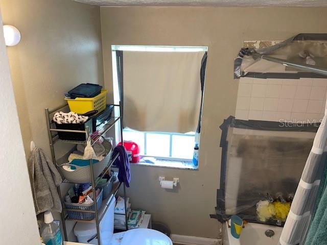 bathroom featuring a washtub, toilet, and baseboards