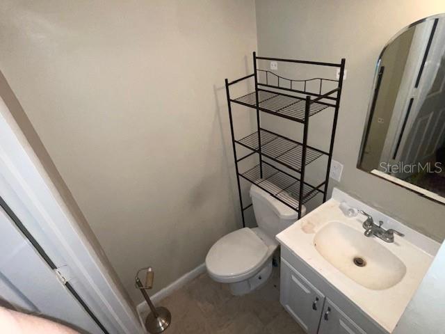 half bathroom with toilet, vanity, and baseboards