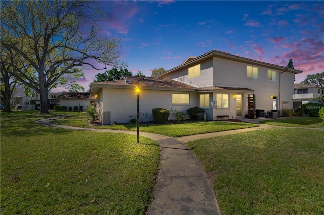 view of front of home with stucco siding, central AC, and a front lawn