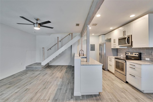 kitchen featuring visible vents, a ceiling fan, tasteful backsplash, light wood-style floors, and appliances with stainless steel finishes