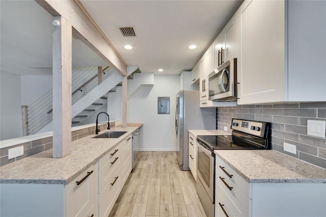 kitchen with tasteful backsplash, visible vents, light stone countertops, stainless steel appliances, and a sink