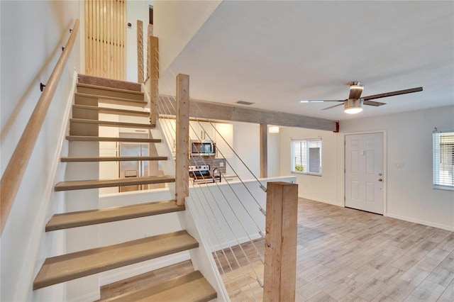 staircase with visible vents, baseboards, wood finished floors, and a ceiling fan