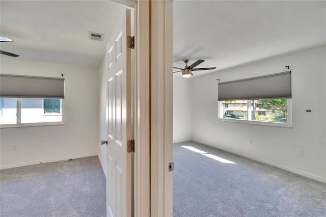 carpeted empty room with a ceiling fan, visible vents, and baseboards