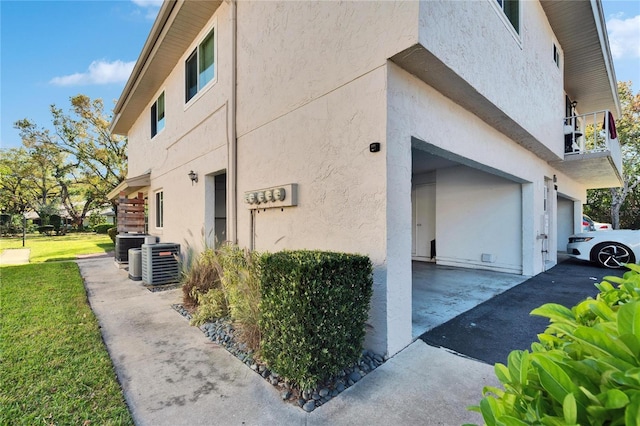 view of property exterior with a garage, central AC unit, and stucco siding