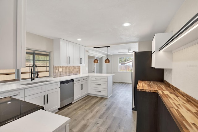 kitchen featuring a sink, white cabinetry, stainless steel appliances, a peninsula, and butcher block counters