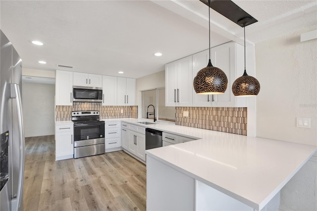 kitchen with a sink, white cabinetry, appliances with stainless steel finishes, light wood finished floors, and decorative backsplash