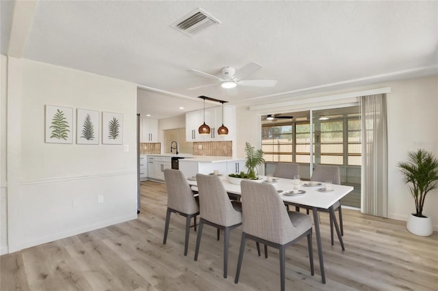 dining area with a ceiling fan, light wood-style floors, visible vents, and baseboards