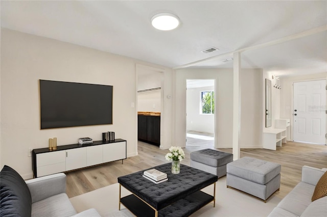 living area featuring light wood-style floors, visible vents, and baseboards