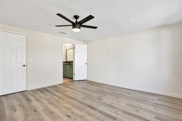 unfurnished bedroom featuring connected bathroom, light wood-style floors, visible vents, and baseboards