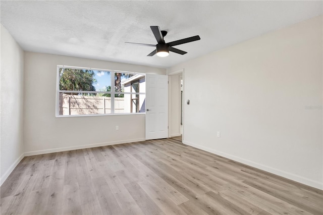 empty room with baseboards, a textured ceiling, and wood finished floors