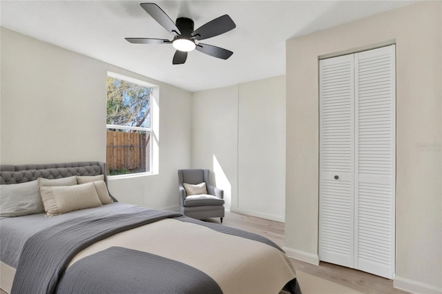 bedroom with baseboards, light wood-type flooring, a closet, and ceiling fan