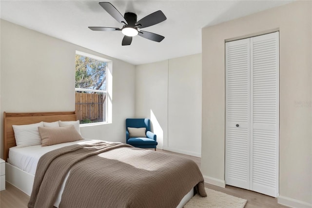 bedroom featuring a closet, light wood finished floors, a ceiling fan, and baseboards