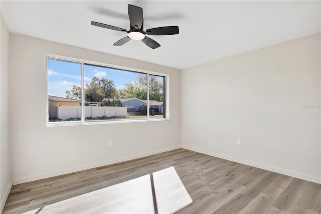 empty room with ceiling fan, baseboards, and wood finished floors