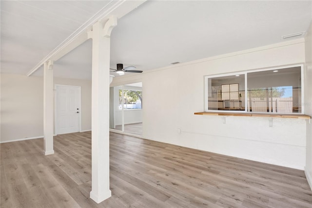 unfurnished living room with ceiling fan, visible vents, wood finished floors, and ornamental molding