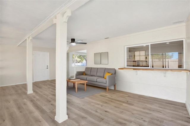 living area with a ceiling fan, crown molding, wood finished floors, and visible vents