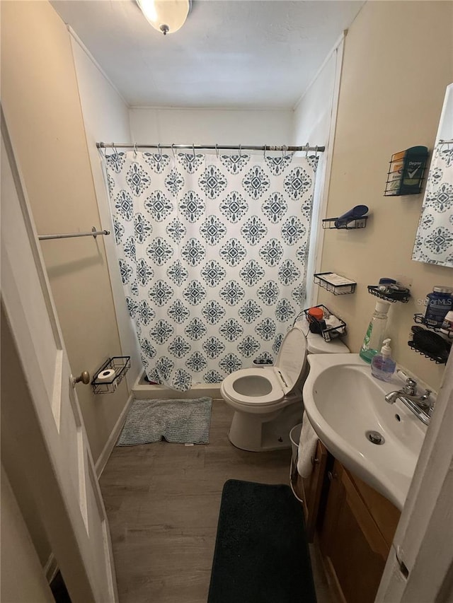 bathroom with vanity, wood finished floors, ornamental molding, a shower stall, and toilet