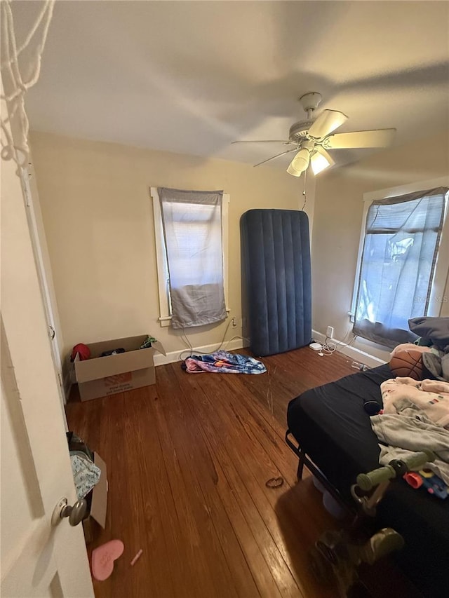 bedroom with baseboards, wood-type flooring, and ceiling fan