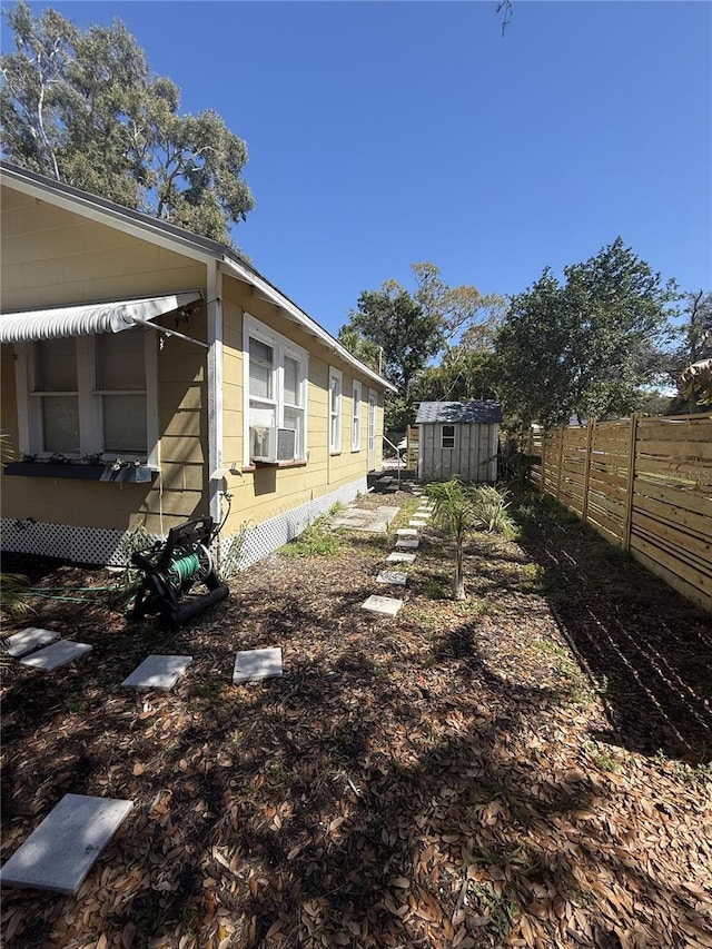 view of yard featuring cooling unit, an outbuilding, fence, and a shed