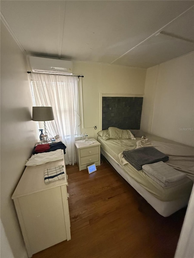 bedroom with a wall mounted air conditioner and wood finished floors