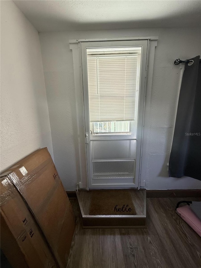 doorway with a textured wall and wood finished floors