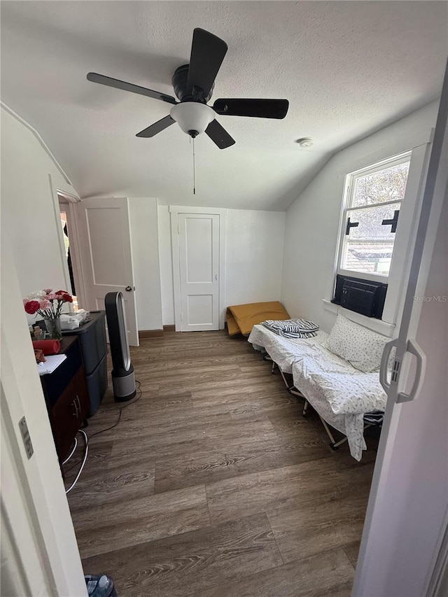 bedroom featuring ceiling fan, a textured ceiling, lofted ceiling, and wood finished floors