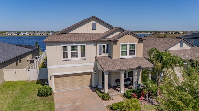 traditional-style home with a gate, fence, a shingled roof, stucco siding, and decorative driveway