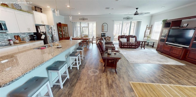 kitchen featuring dark wood-type flooring, a sink, tasteful backsplash, stainless steel appliances, and crown molding