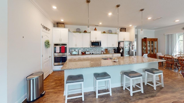 kitchen featuring decorative backsplash, appliances with stainless steel finishes, a breakfast bar area, and crown molding