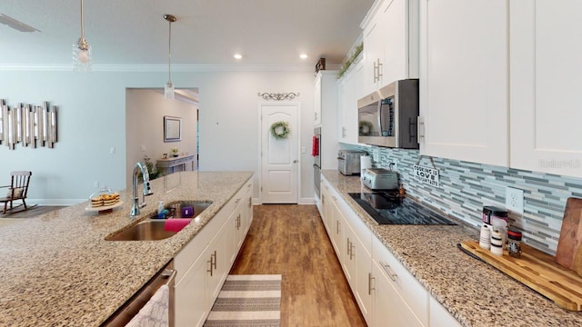 kitchen with a sink, ornamental molding, stainless steel appliances, white cabinetry, and backsplash