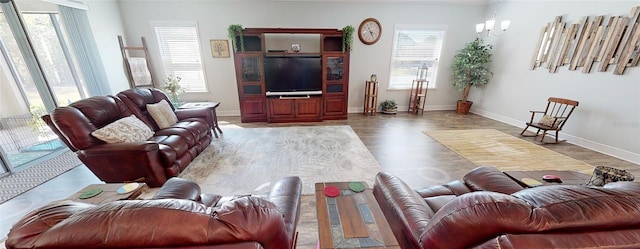 living room featuring a notable chandelier, wood finished floors, baseboards, and a wealth of natural light